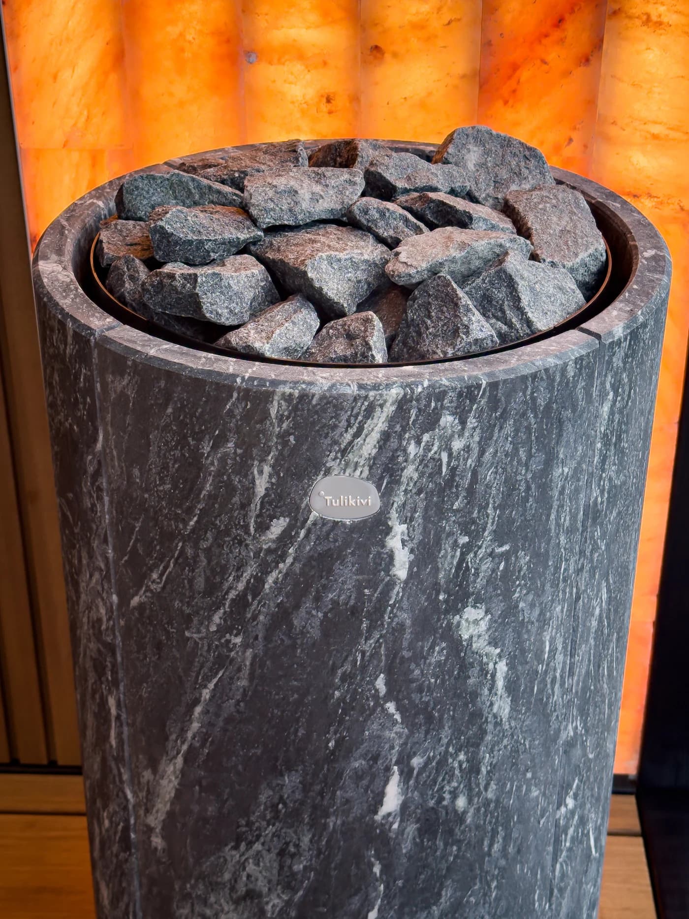 Stone-clad sauna heater photographed beside an illuminated salt wall