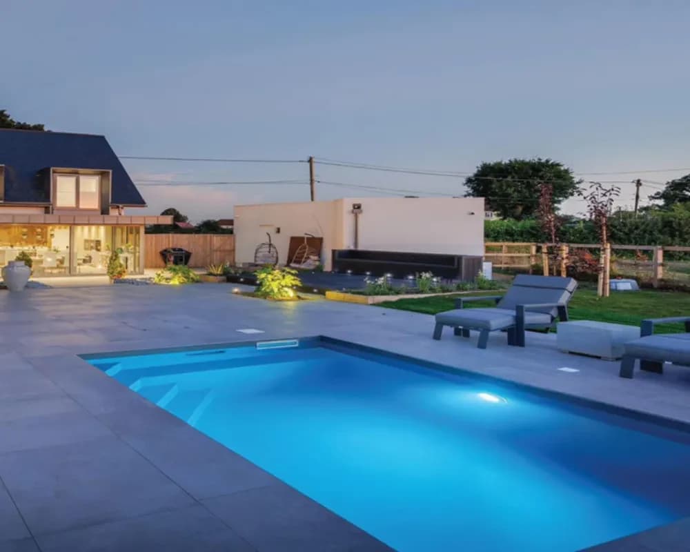 Outdoor pool illuminated beside a contemporary home